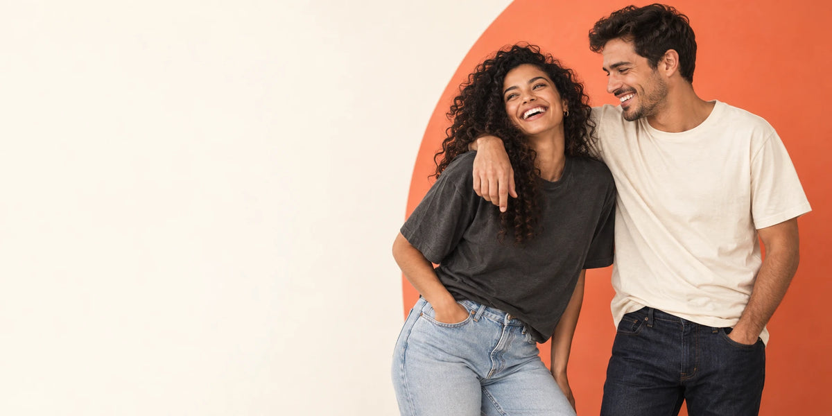 Two friends laughing in charcoal and cream T-shirts against a warm cream and coral MoodRally backdrop.
